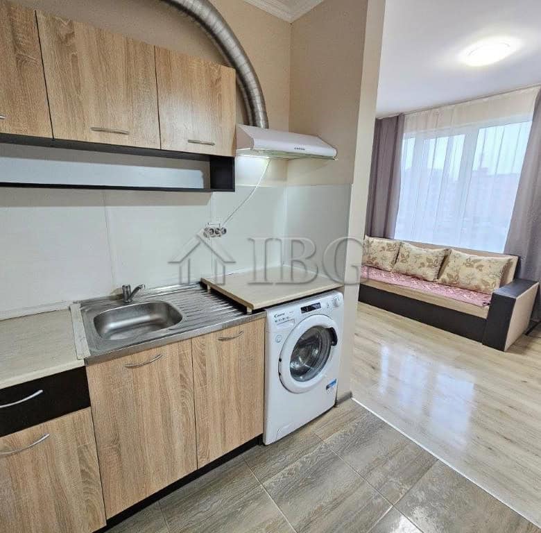 Compact studio kitchen with modern appliances and wooden cabinets.