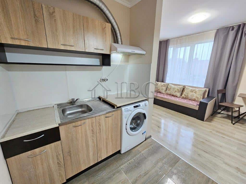 Compact studio kitchen with modern appliances and wooden cabinets.