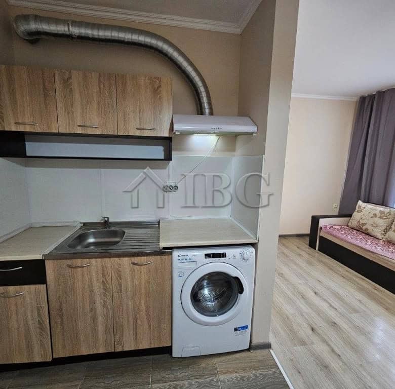 Compact studio kitchen with washing machine and modern cabinetry.