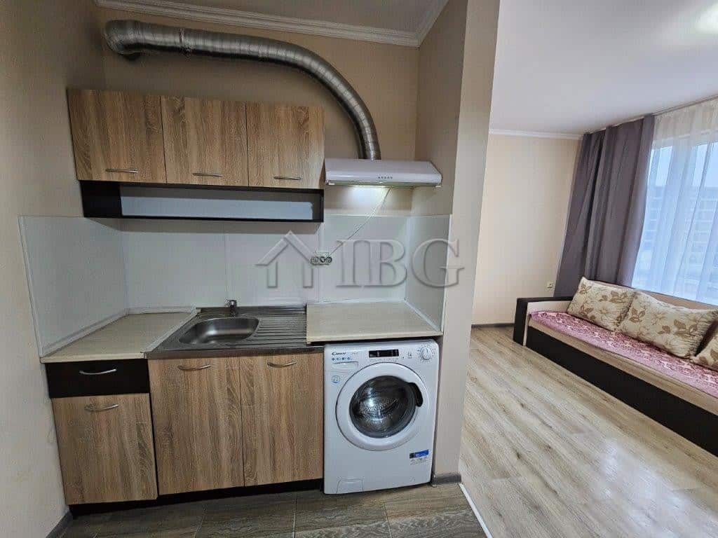 Compact studio kitchen with washing machine and modern cabinetry.
