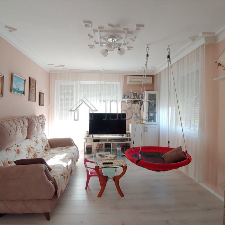 Bright living room with sofa, TV, and cozy swing in Kosharitsa home.