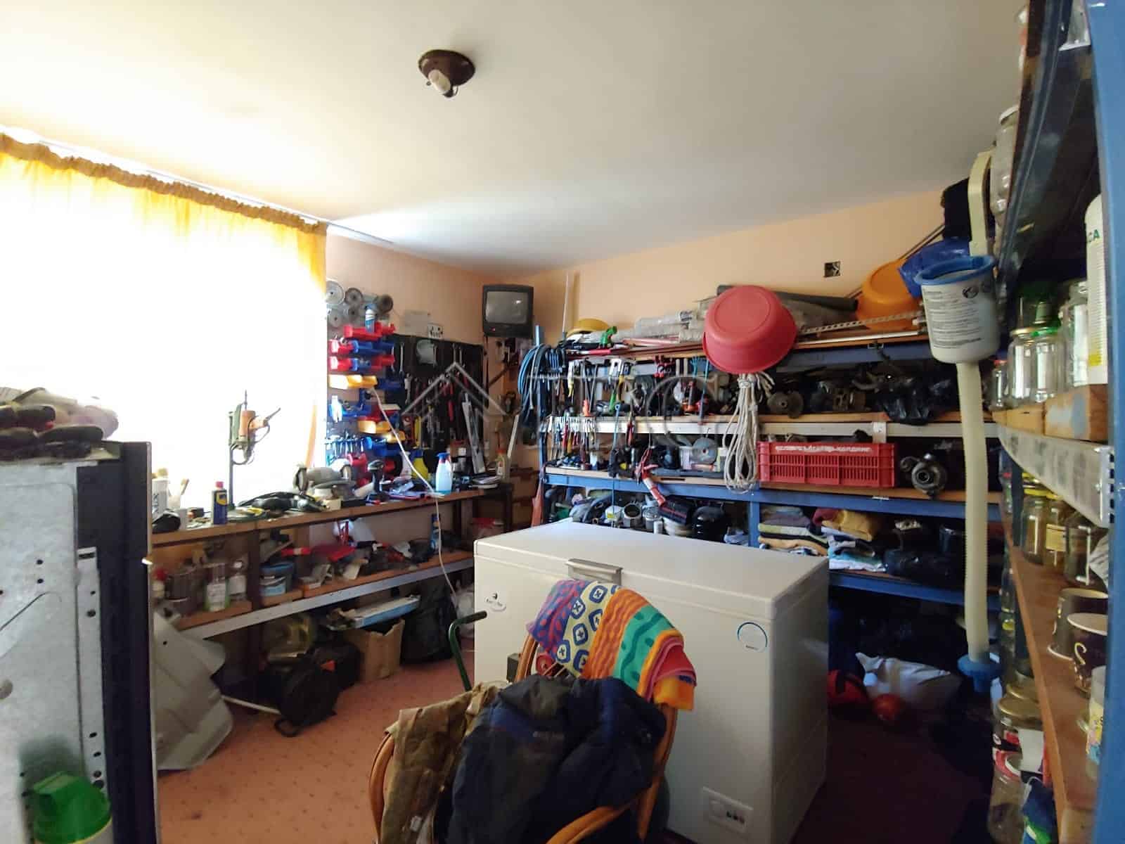 Interior view of a well-organized storage room with shelves filled with tools and household items.