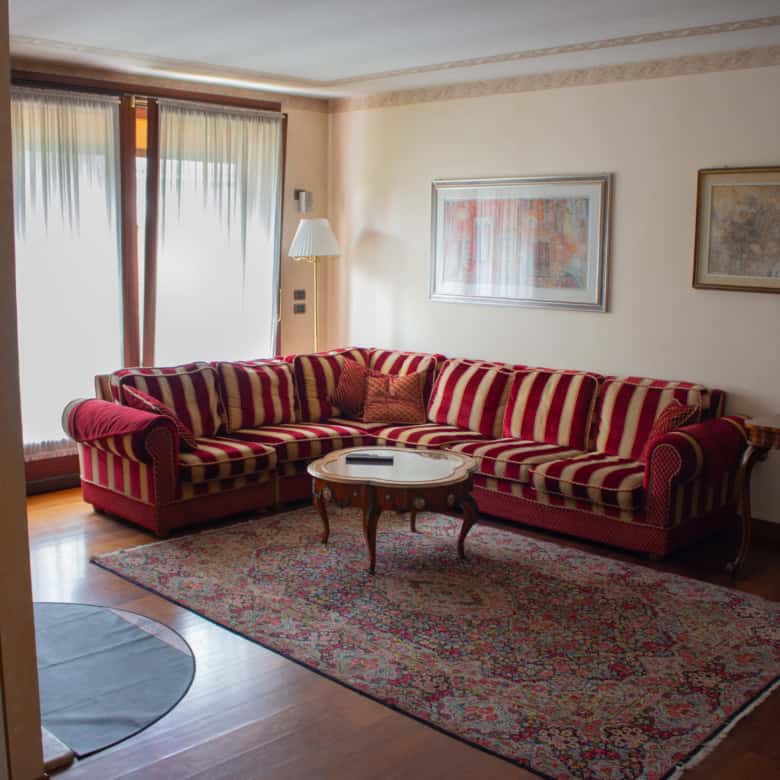 Living room with red striped sofa, artwork, and natural light from balcony.
