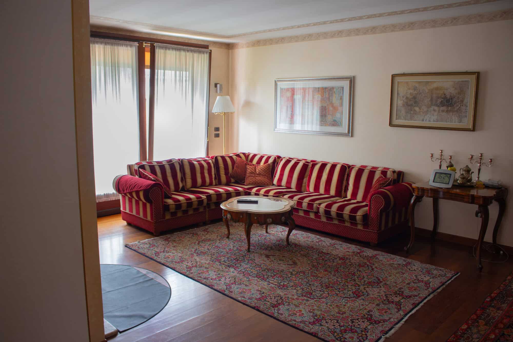 Living room with red striped sofa, artwork, and natural light from balcony.