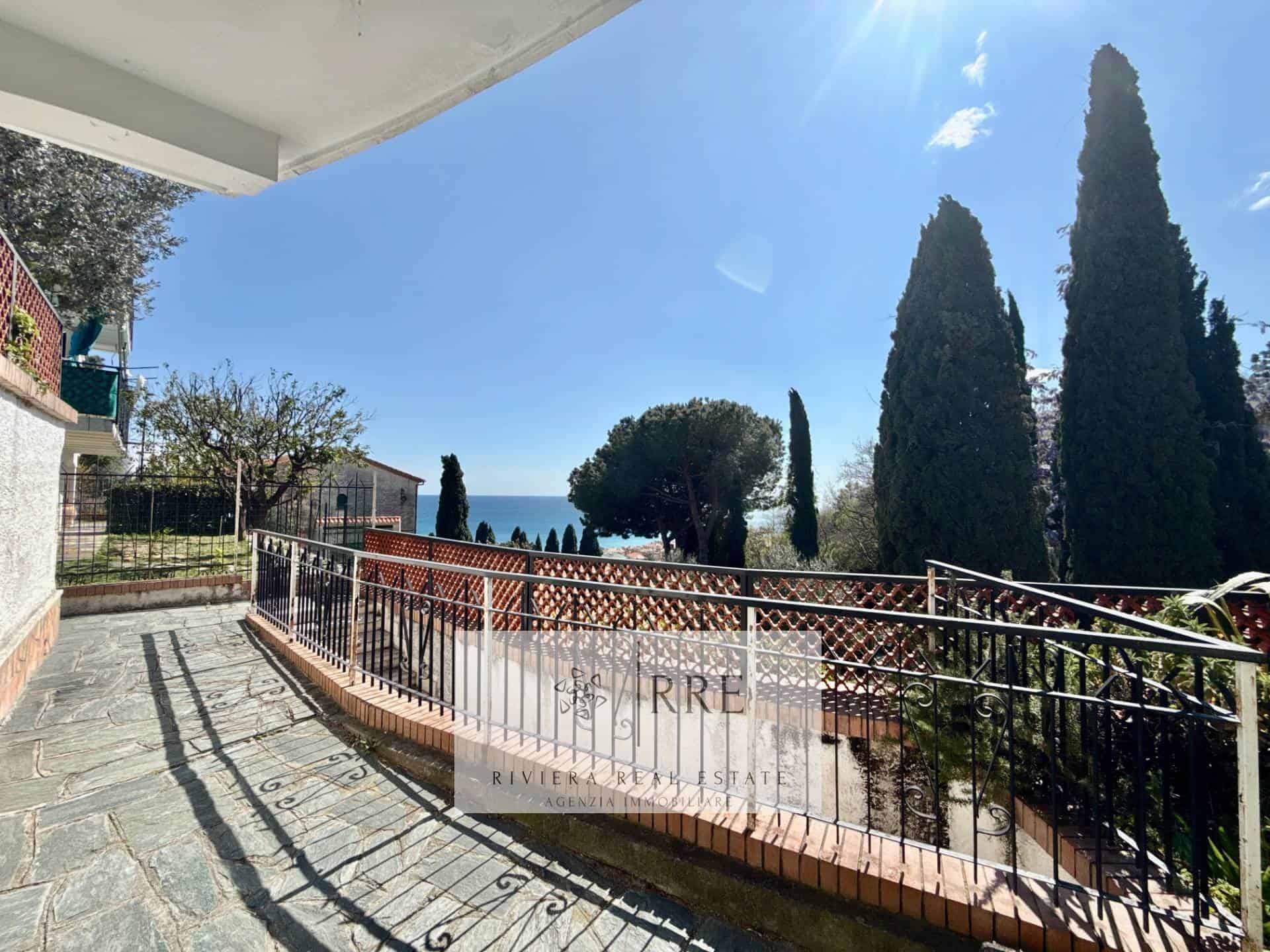 Elegant terrace overlooking the sea with tall cypress trees and lush garden scenery.