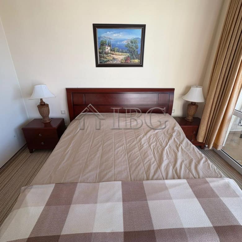 Bedroom with a double bed, nightstands, and lamps in a sunny apartment at Majestic Beach Resort.