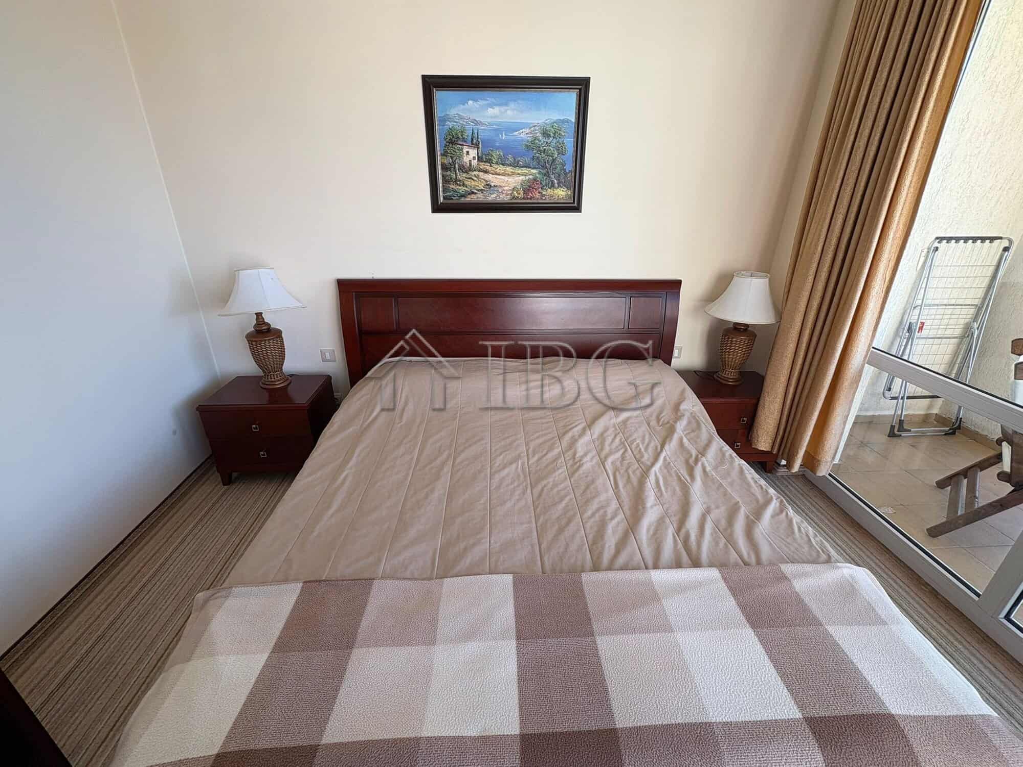 Bedroom with a double bed, nightstands, and lamps in a sunny apartment at Majestic Beach Resort.