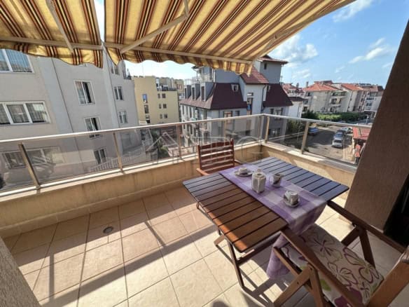Bright balcony view of Ravda residential building with outdoor dining setup.