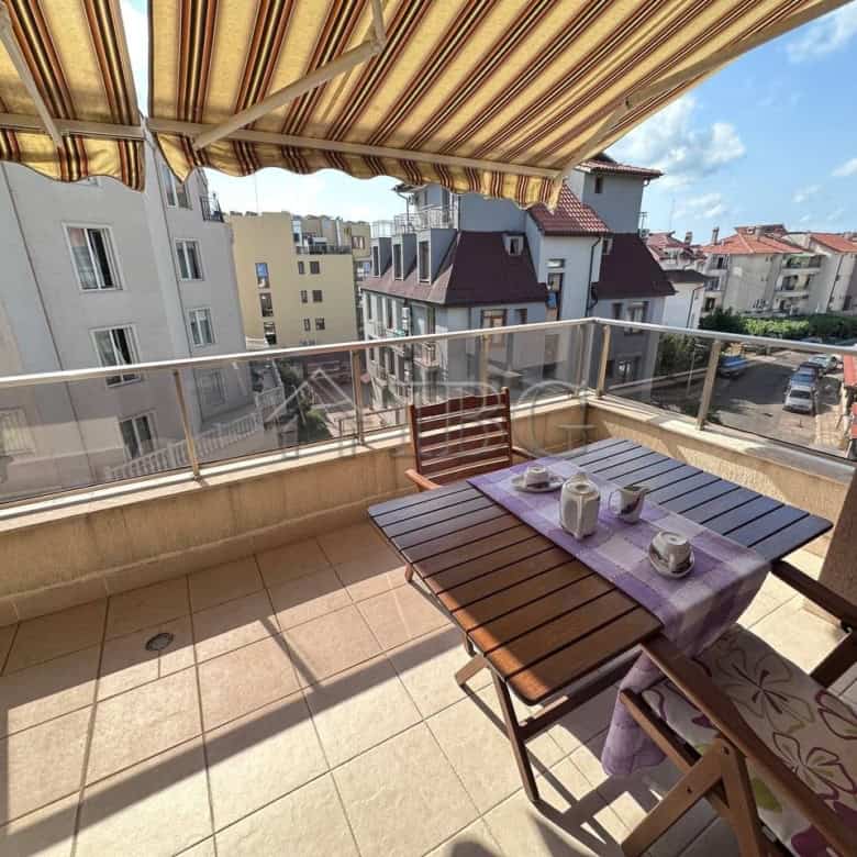 Bright balcony view of Ravda residential building with outdoor dining setup.
