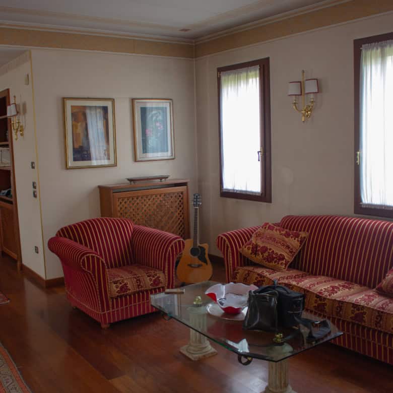 Spacious living room featuring classic furniture, artwork, and natural light from large windows.