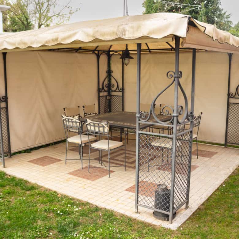 Outdoor garden gazebo with metal frame, beige canopy, and seating for outdoor relaxation.