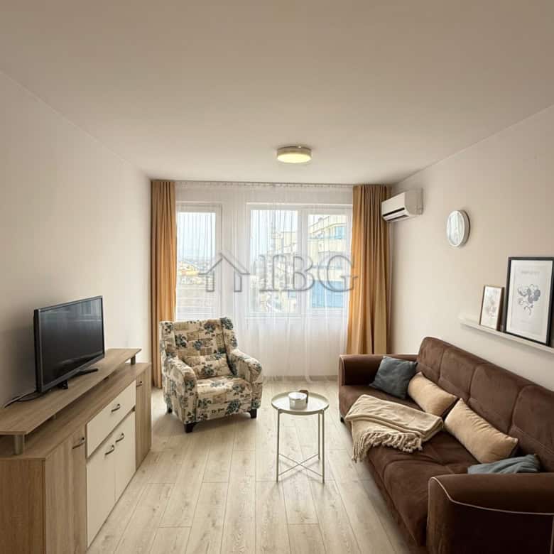 Bright living room with sofa, armchair, and TV in Pomorie Beach Resort.