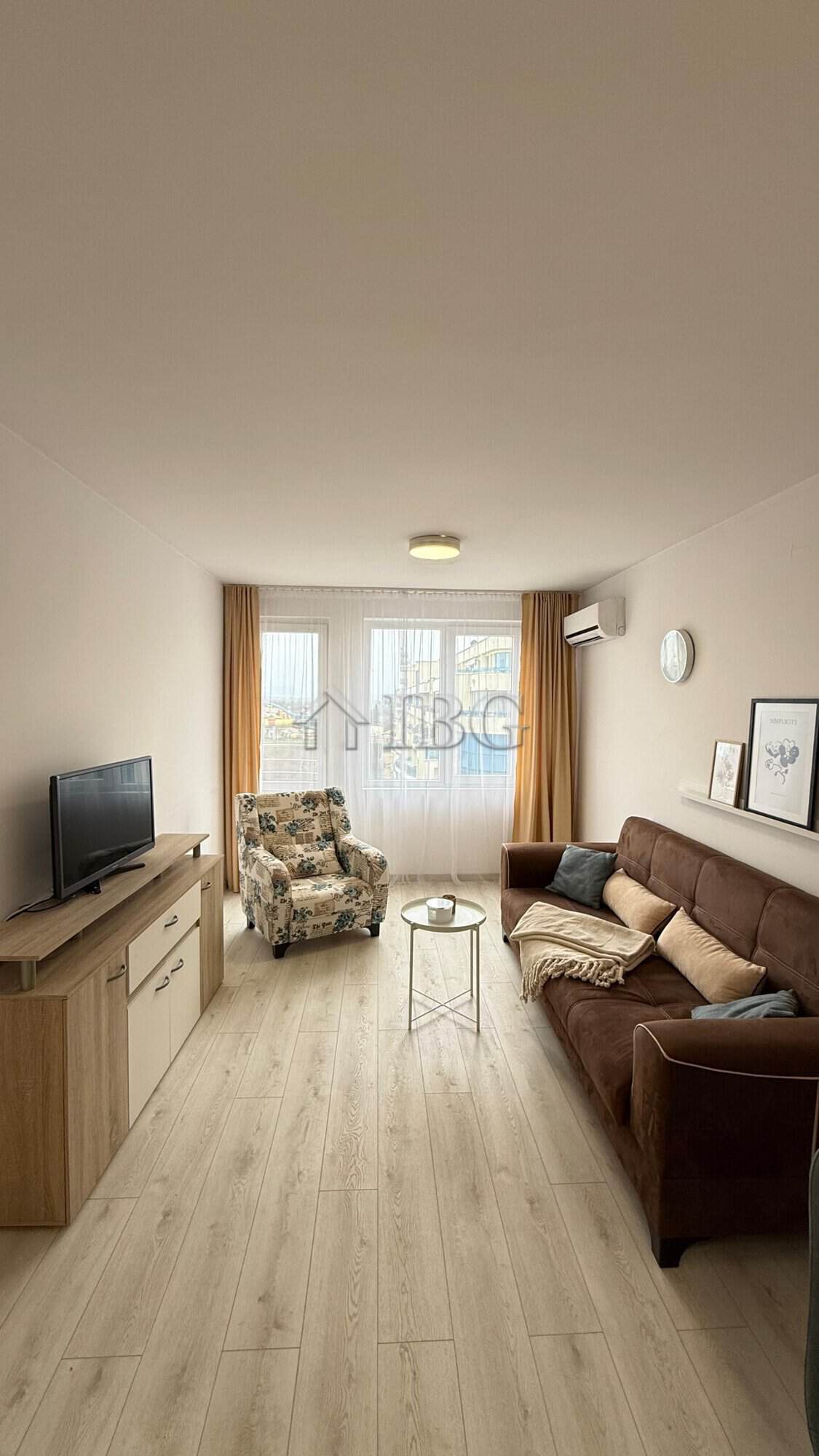 Bright living room with sofa, armchair, and TV in Pomorie Beach Resort.