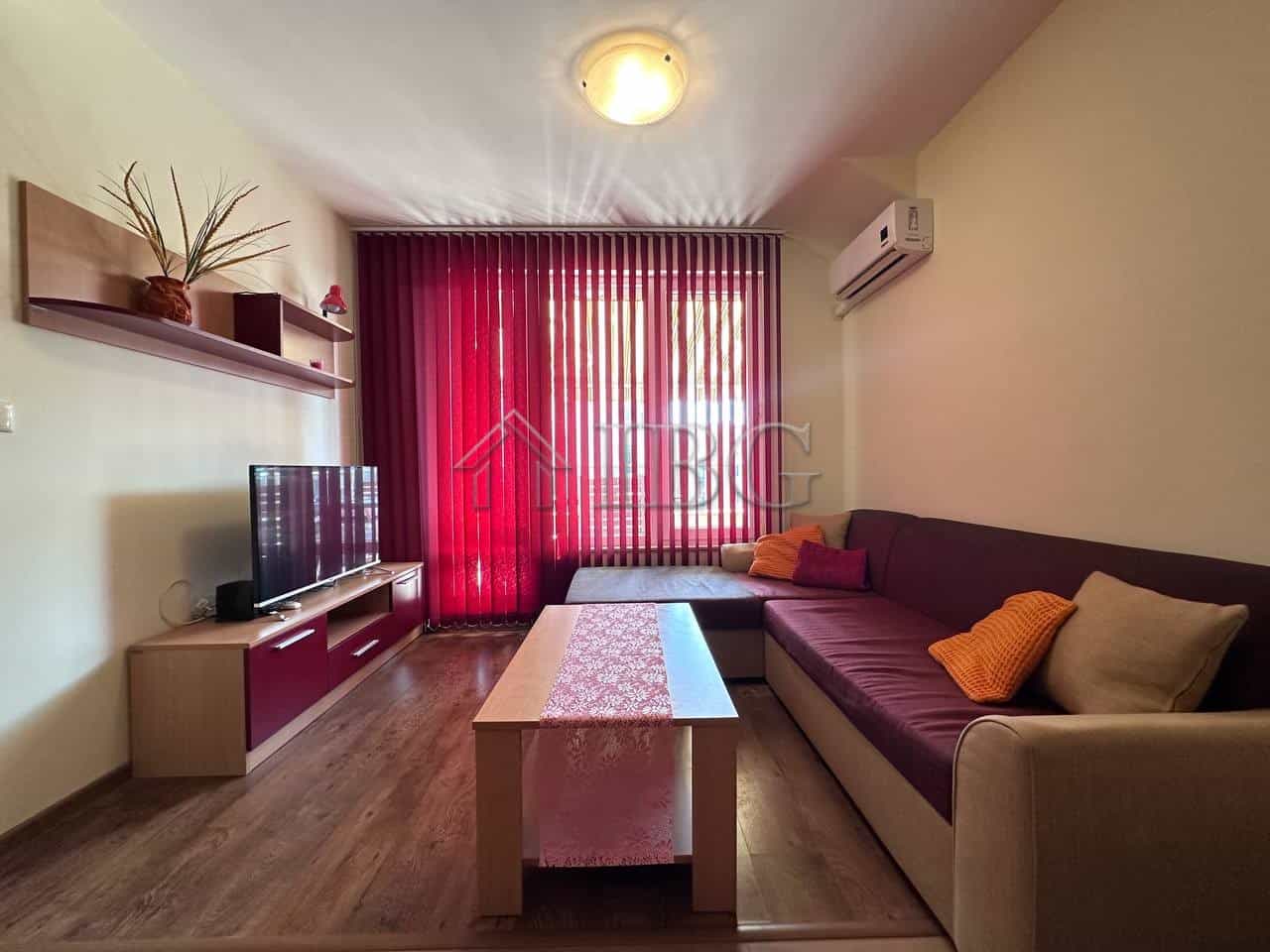 Cozy 1-bedroom apartment in Ravda with living room, TV, and colorful cushions.