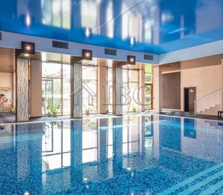Indoor swimming pool with large windows and bright lighting.