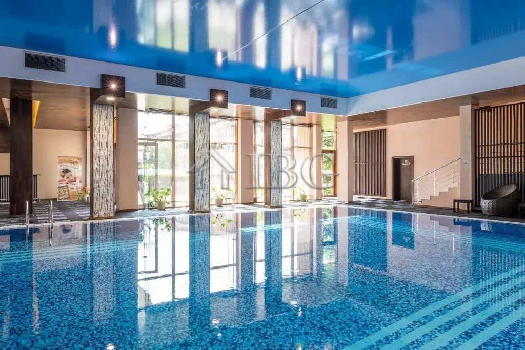 Indoor swimming pool with large windows and bright lighting.