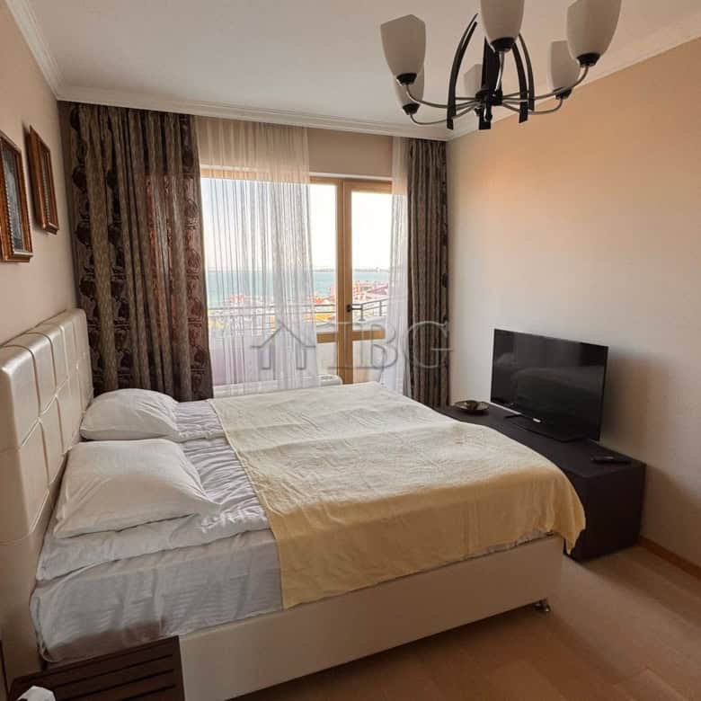 Bright bedroom with large window overlooking sea and mountains, modern decor, and comfortable bed.