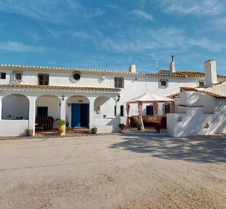Charming boutique hotel in Caniles, Granada, Spain with whitewashed walls and outdoor seating area.