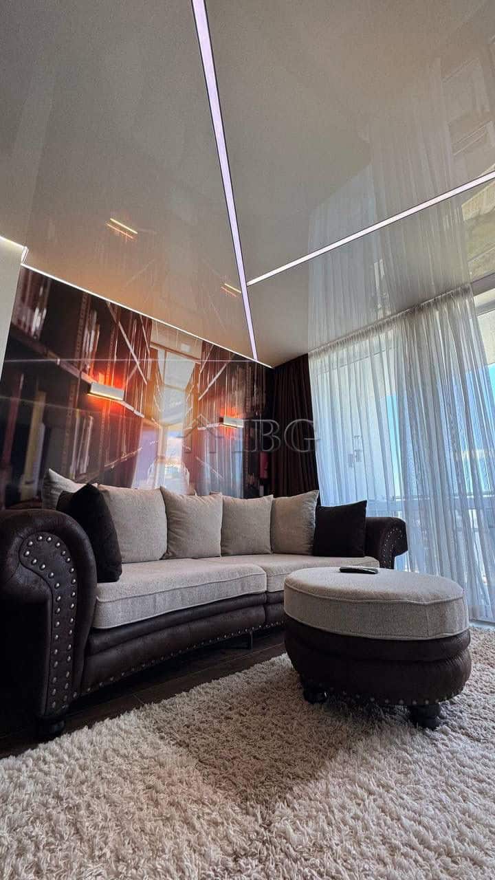 Modern living room with ceiling LED lights and large window overlooking the city.