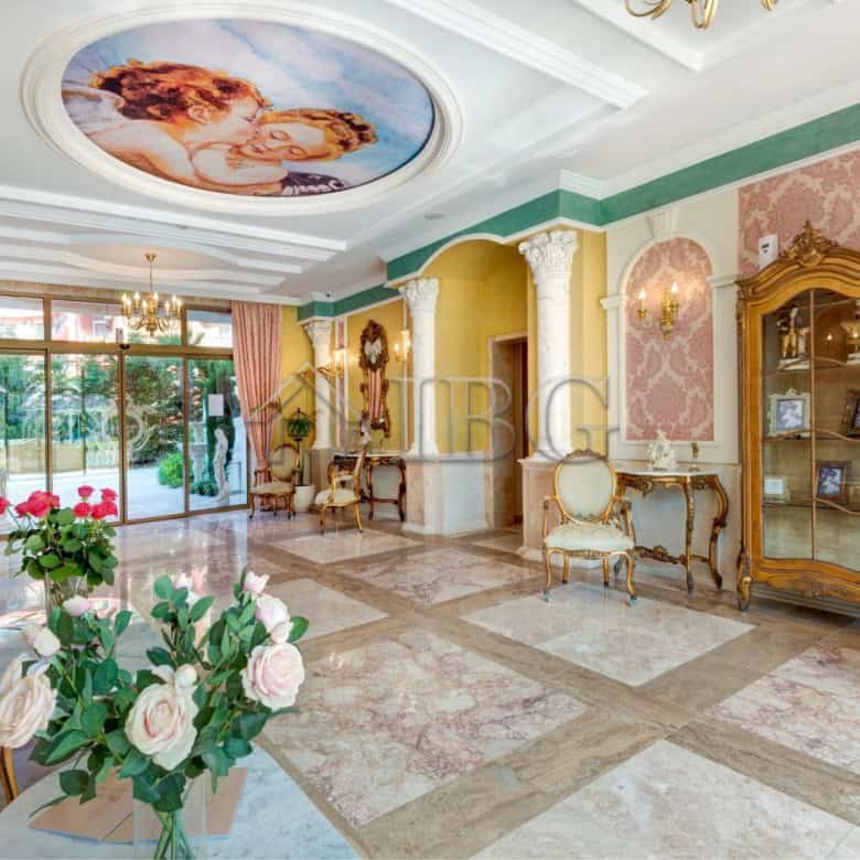 Luxurious living space featuring ornate furniture, decorative columns, and a beautiful ceiling mural.