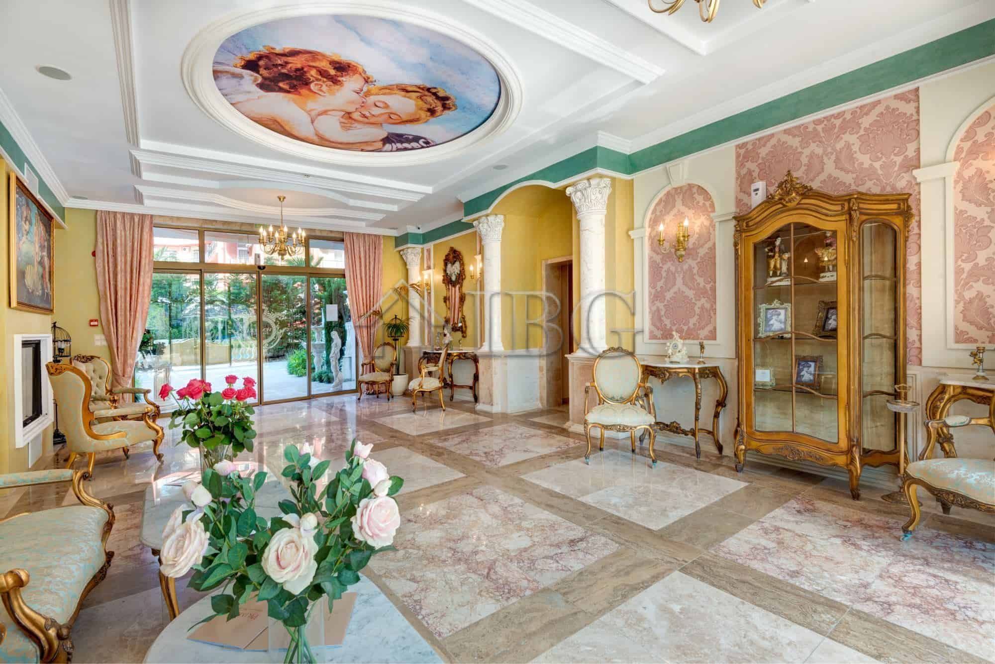 Luxurious living space featuring ornate furniture, decorative columns, and a beautiful ceiling mural.