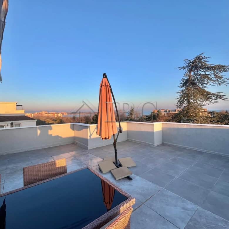 Terrace with sea view, umbrella, and outdoor furniture in Ravda apartment.