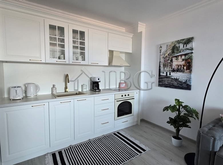 Bright, open-plan kitchen featuring white cabinetry, appliances, and a cozy living area.