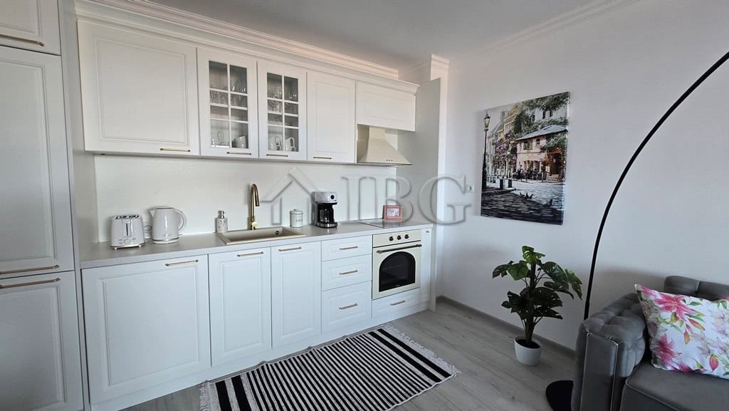 Bright, open-plan kitchen featuring white cabinetry, appliances, and a cozy living area.