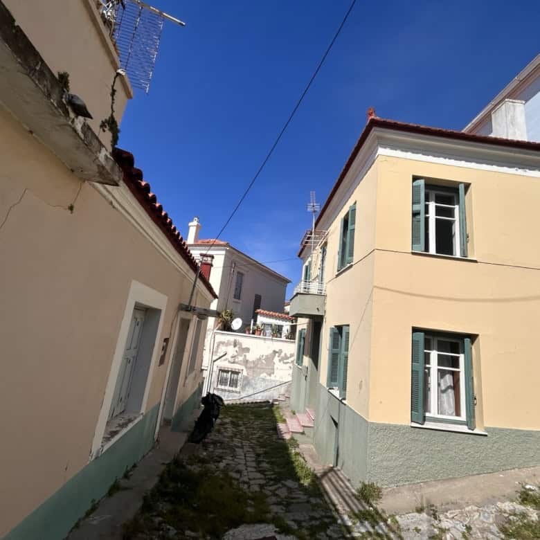 Cozy Mediterranean-style house with pastel yellow walls and green window shutters in Portugal.