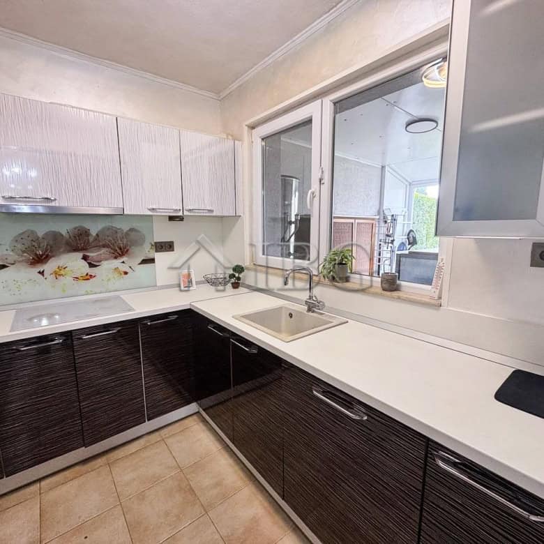 Modern kitchen with sea views, white and dark cabinetry, and large window overlooking the coast.