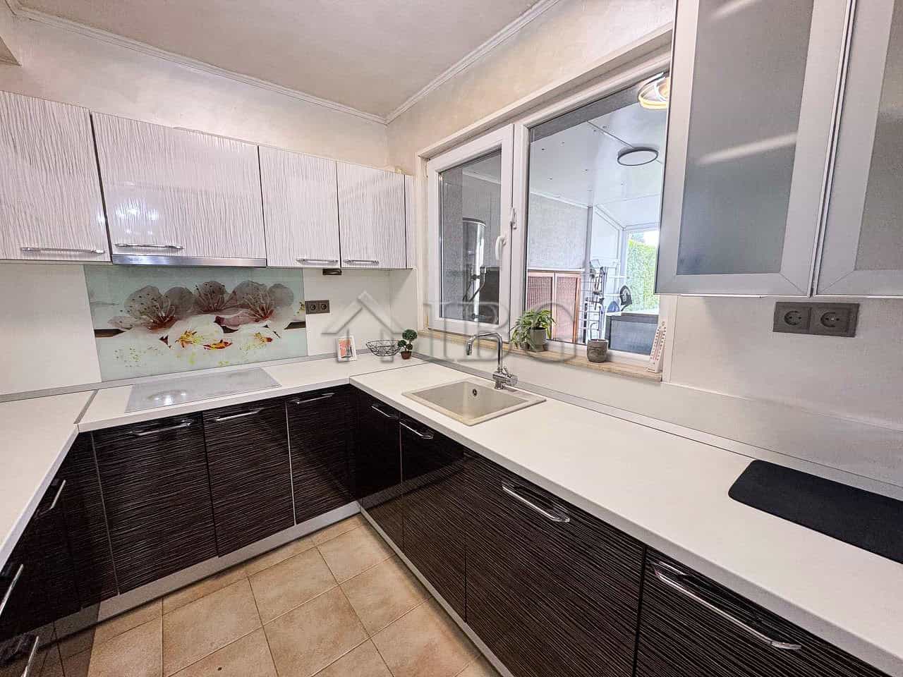 Modern kitchen with sea views, white and dark cabinetry, and large window overlooking the coast.