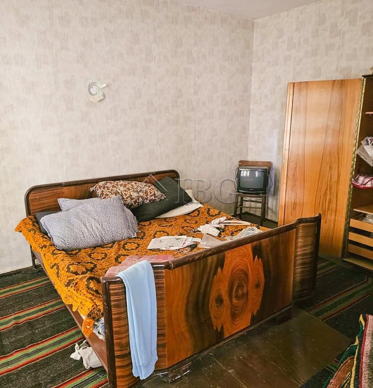 Spacious bedroom featuring a wooden bed frame, colorful rugs, and ample natural light. Ideal for ren.