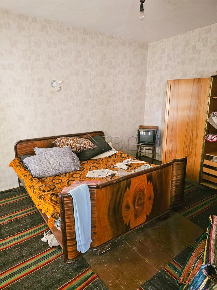 Spacious bedroom featuring a wooden bed frame, colorful rugs, and ample natural light. Ideal for ren.