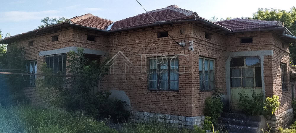 Brick house with renovated roof and garden in a peaceful village setting.