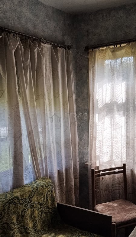 Interior view of a cozy room featuring curtains, vintage furniture, and natural light.