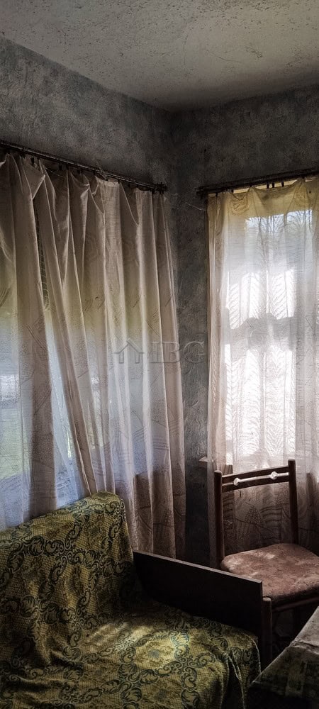 Interior view of a cozy room featuring curtains, vintage furniture, and natural light.