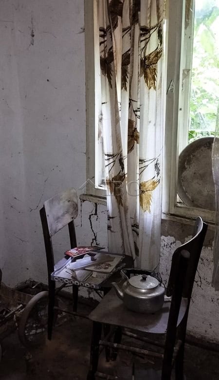 Old curtains hanging by a window in a rustic, abandoned room.