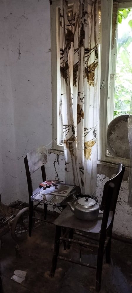 Old curtains hanging by a window in a rustic, abandoned room.