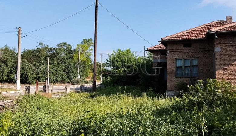 Traditional brick house with renovated roof and large garden in a peaceful village setting.