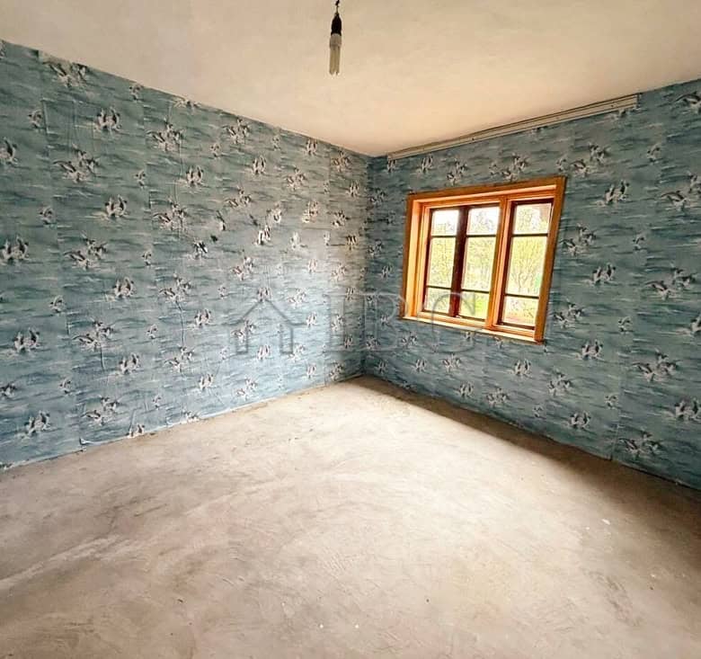 Interior of a partly renovated house with blue patterned walls and a large window.
