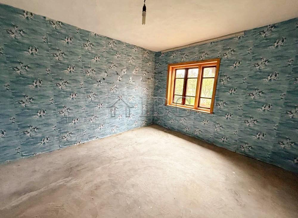 Interior of a partly renovated house with blue patterned walls and a large window.