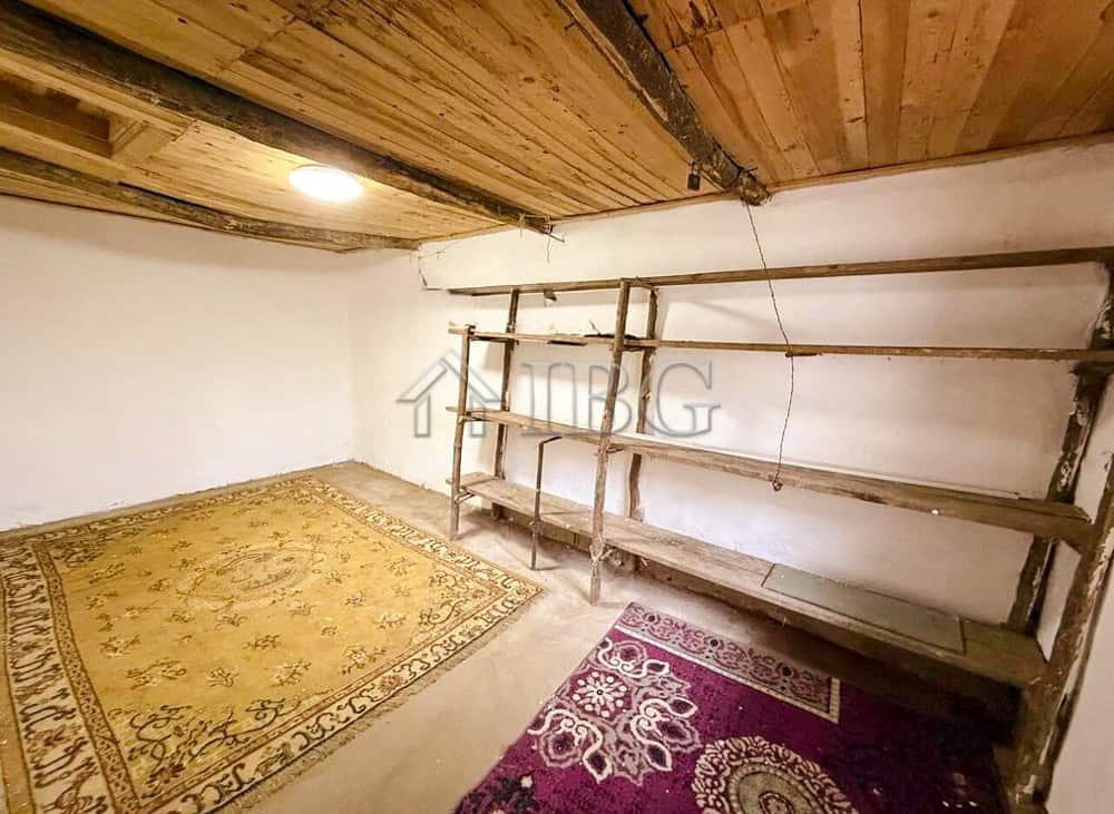 House interior with wooden ceiling and shelves, partially renovated with carpets on the floor.