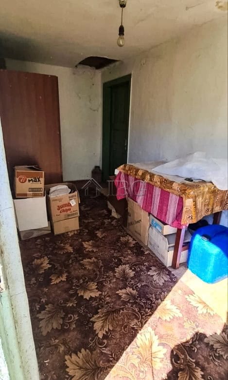Interior view of a rustic room with basic furnishings and storage boxes.
