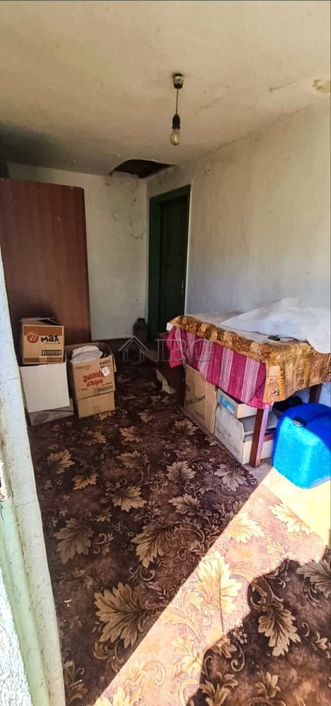 Interior view of a rustic room with basic furnishings and storage boxes.