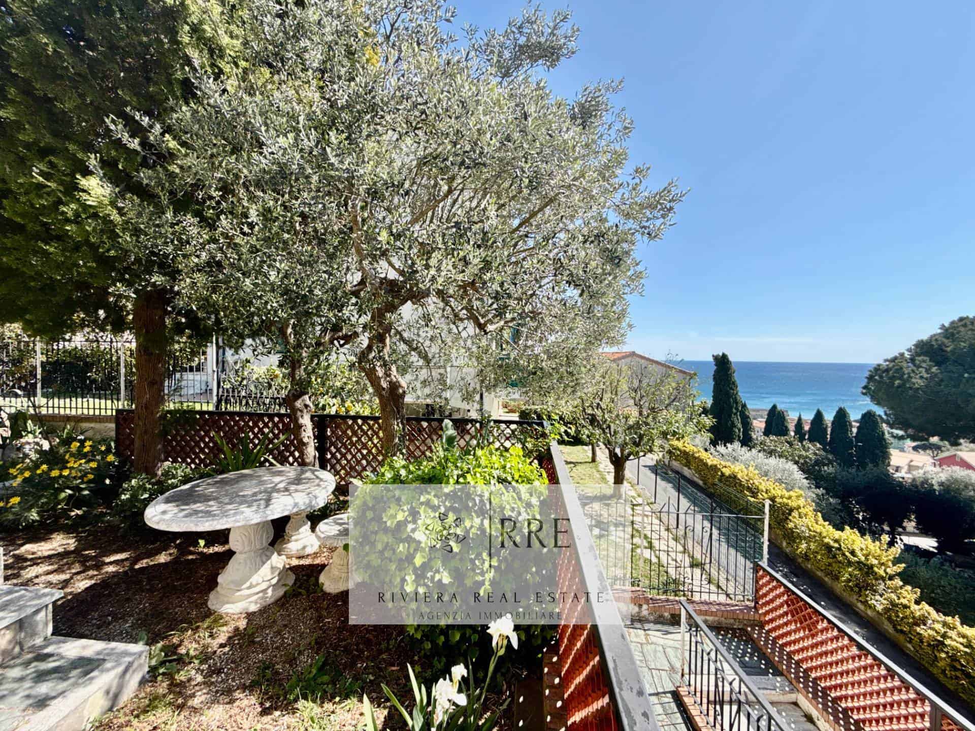 Coastal garden with mature trees, lush greenery, and a stunning ocean view in the background.