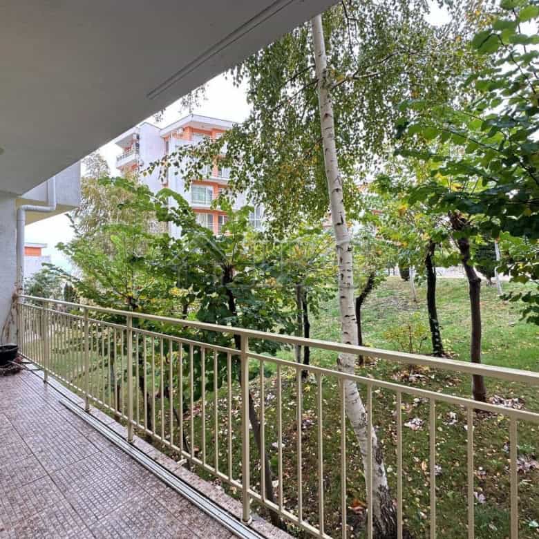 Balcony of ground floor apartment overlooking lush garden and trees.