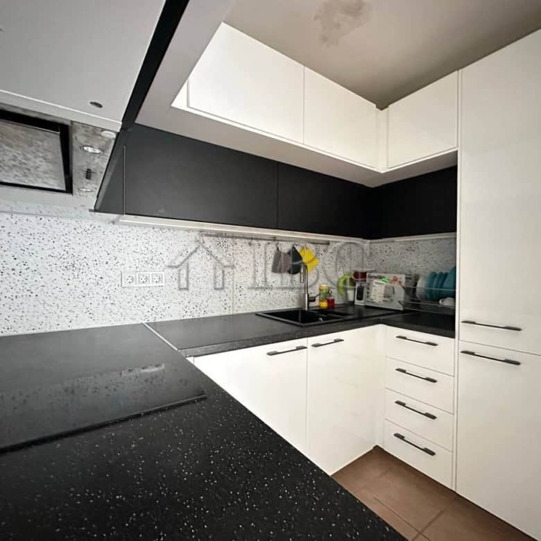 Contemporary kitchen with white cabinets and black countertops in Sveti Vlas apartment.