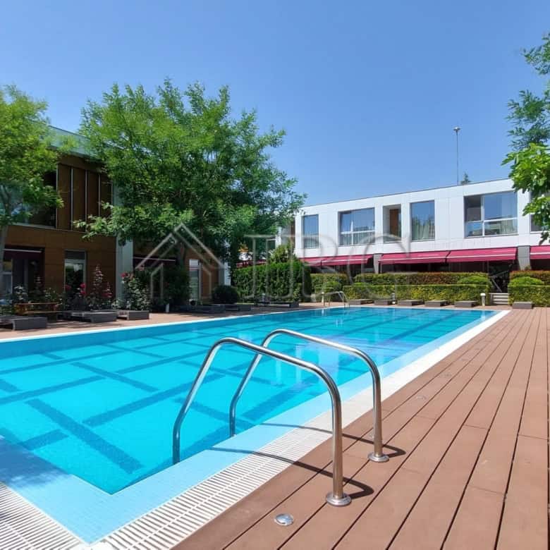 Modern townhouse with outdoor pool and wooden deck in a lush green setting.
