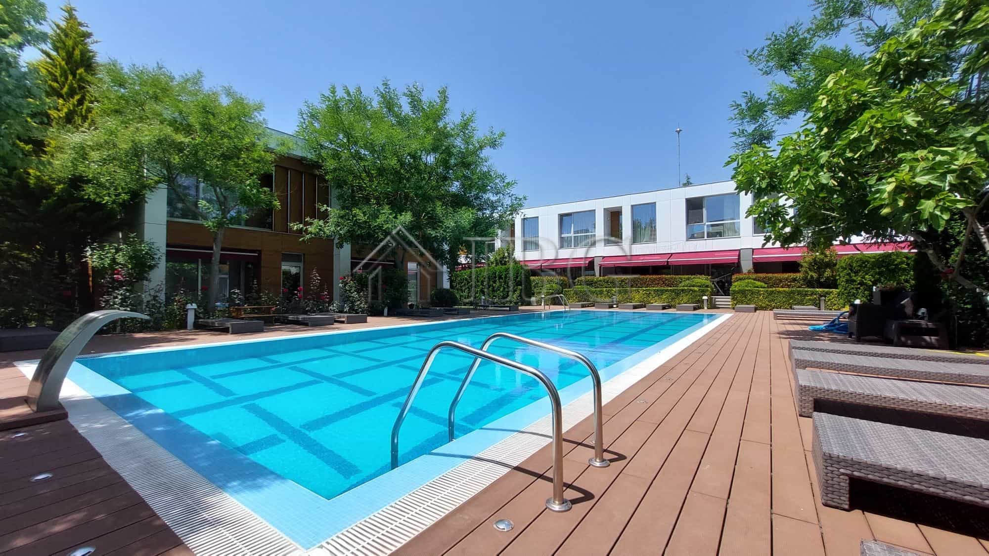 Modern townhouse with outdoor pool and wooden deck in a lush green setting.
