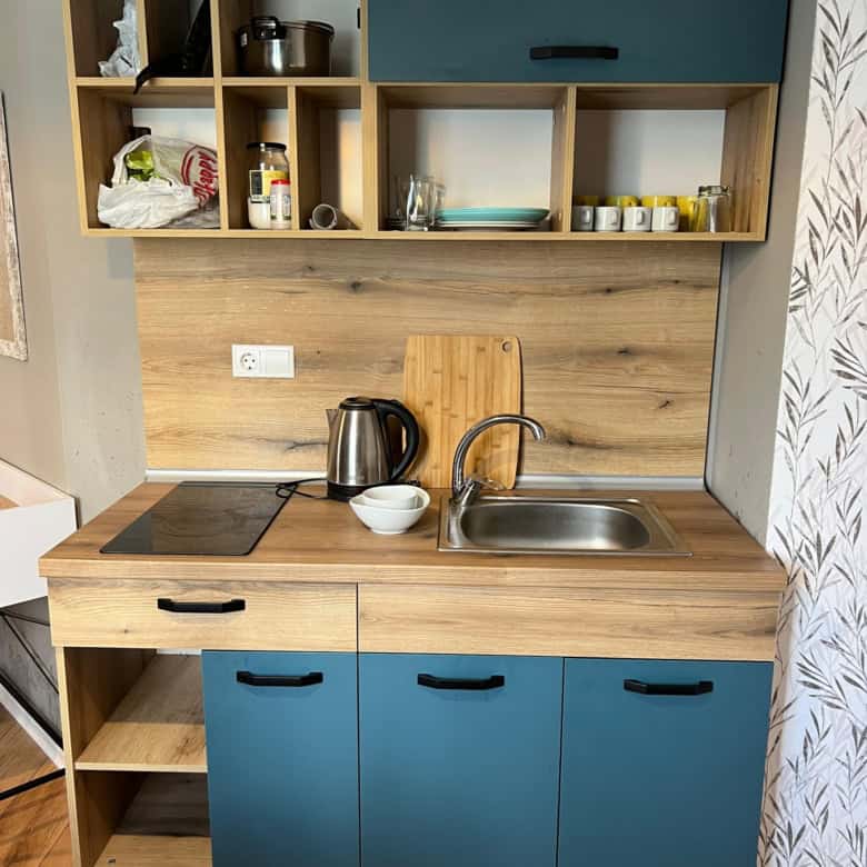 Compact studio kitchen with blue cabinets and open shelving in Saint Vlas.